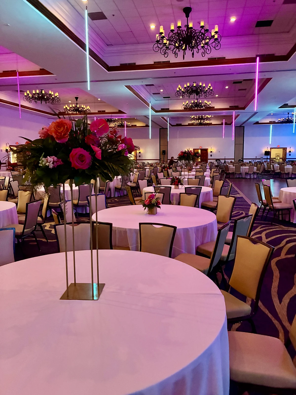 Wide ballroom view at the Ionis 2025 holiday party at Omni La Costa, with floral centerpieces across round dining tables